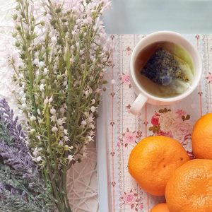 aerial view of teacup with tea bag in it beside lavender clippings and oranges